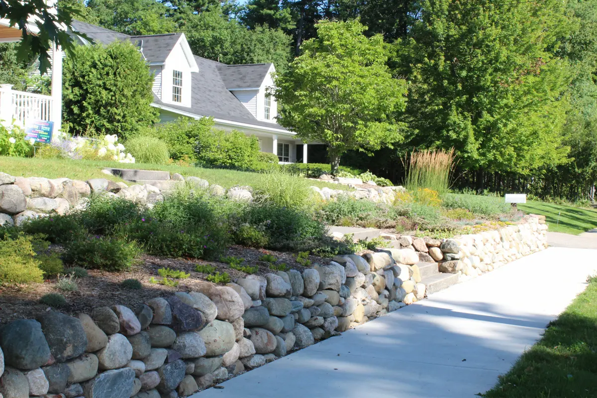 Stone retaining walls with tiered garden and white house