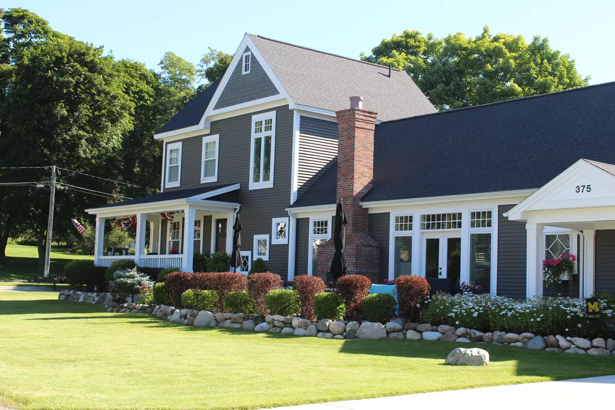 Large dark siding house with white trim and landscaped yard