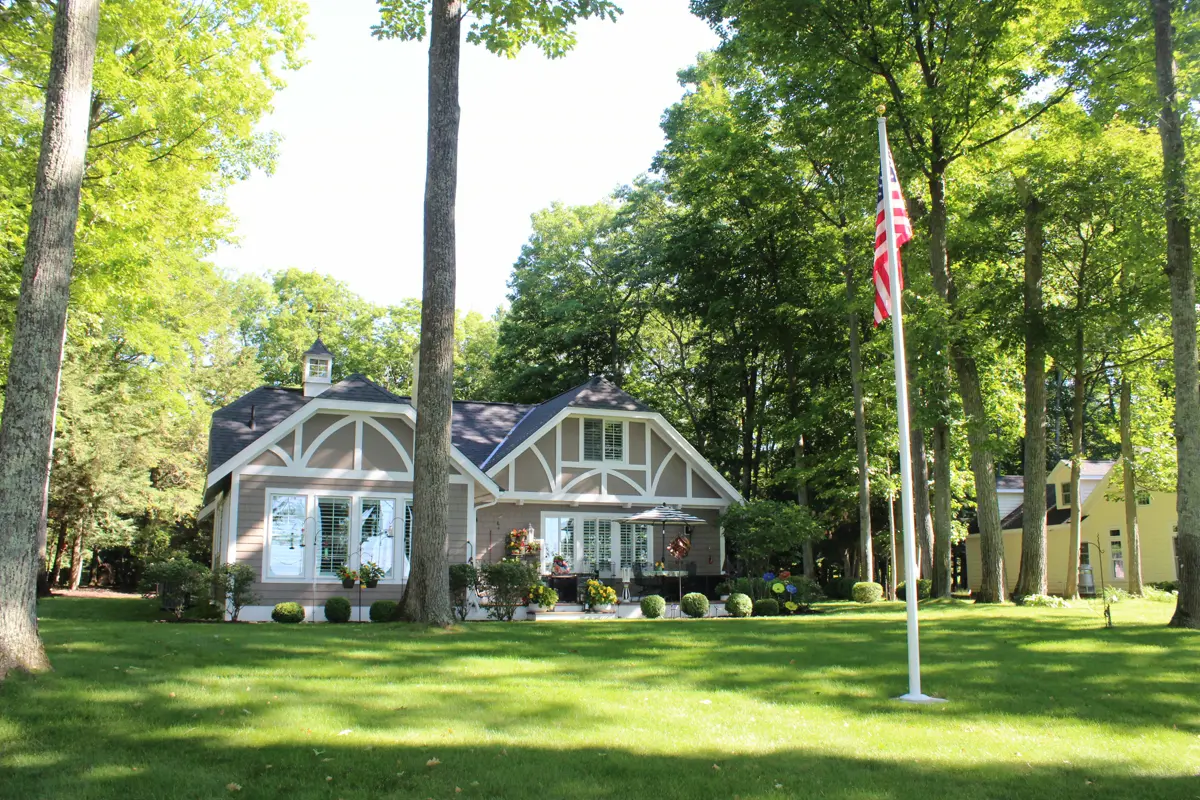 Tudor style cottage with American flagpole on green lawn