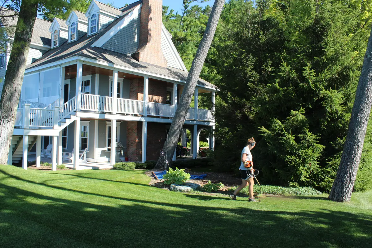 Two-story house with wraparound porch surrounded by trees