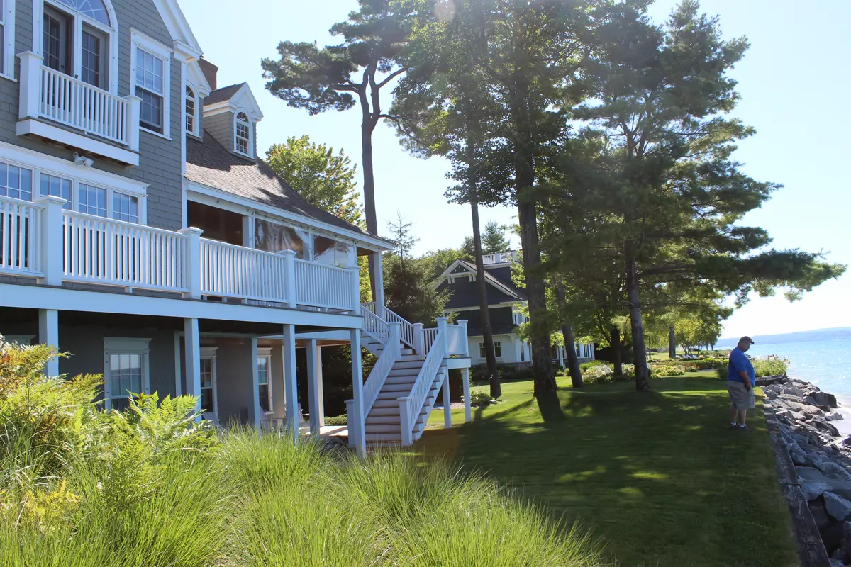Waterfront home with white deck overlooking rocky shoreline